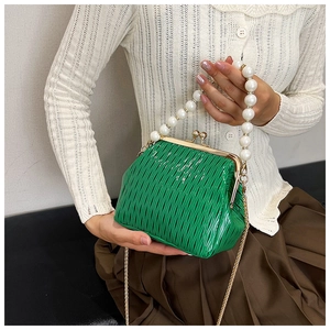 Detail of emerald green pleated bag featuring pearl handle and gold chain strap