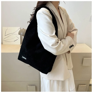 Détail du sac cabas en velours côtelé noir avec étiquette FASHION porté par un mannequin