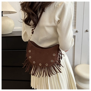 Gros plan sur un sac bandoulière en daim marron avec de longues franges et œillets dorés