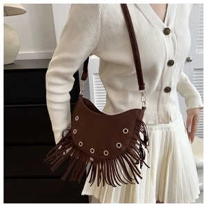 Detail of dark brown suede tassel bag with golden eyelets and sleek moon saddle shape