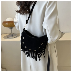 Detail of black crescent suede crossbody bag with long tassels and gold metal eyelets
