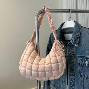 Détail du sac nuage matelassé rose clair avec bandoulière plissée sur un cintre