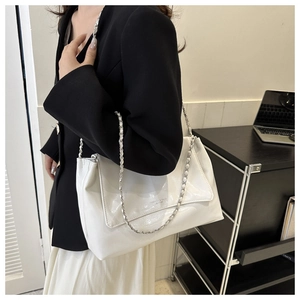 Detail of white patent leather tote bag with silver chain strap and logo lettering