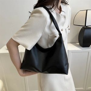 Minimalist black faux leather shoulder bag worn with a tweed jacket for a commute look