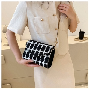 Primer plano de bolso bandolera de tweed a cuadros blanco y negro con cadena dorada