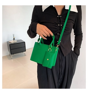 Detail of vibrant green quilted handbag with matching small pouch charm and gold hardware