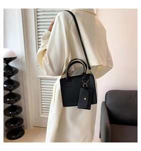 Detail of black quilted shoulder bag with gold hardware and a small round coin purse