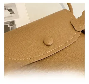 Detailed view of caramel brown leather bag featuring precision stitching and lychee texture