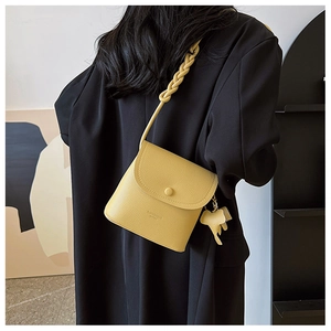 Detail of yellow lychee leather mini crossbody bag with braided strap and elephant charm