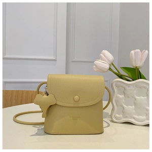 Close-up of cream leather bucket bag featuring a cute elephant charm and pebble texture