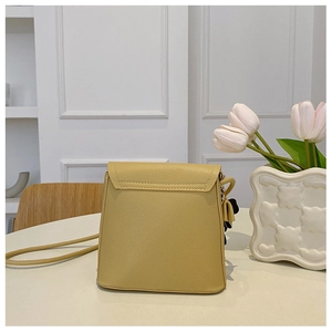 Detail view of mustard yellow pebbled leather bucket bag on an aesthetic indoor table