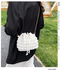 Détail d'un sac seau blanc à texture bulles avec bandoulière en chaîne dorée