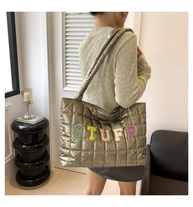 Detailed view of bronze quilted tote bag featuring colorful chenille stuff embroidery
