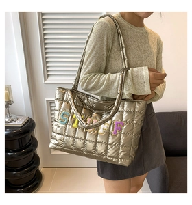 Detail of gold metallic quilted tote bag with STUFF plush letter embroidery and stitching