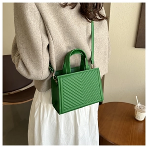 Detail of green quilted handbag with V-stitch pattern and adjustable shoulder strap