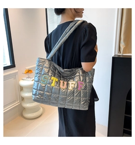 Close-up of quilted silver puffer tote bag with colorful STUFF lettering and padded handles