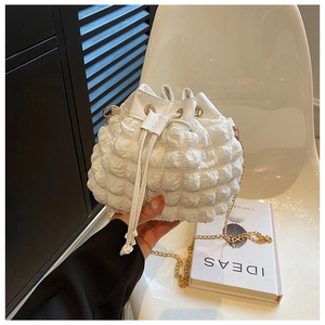 Détail du sac seau blanc à texture bulles avec fermeture à cordon et chaîne dorée