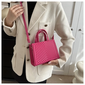 Close-up of fuchsia mini square bag with V-quilted texture and gold-tone hardware