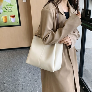 Large cream leather tote bag with brown straps and gold ring hardware shown on model