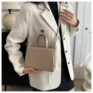 Detail of light khaki quilted crossbody bag featuring V-shaped stitching and gold lock