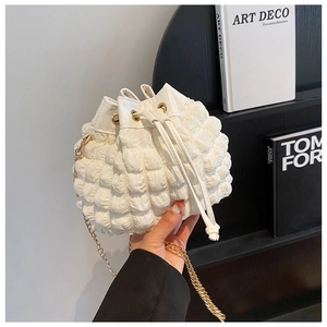Détail du sac seau blanc à texture bulle avec chaîne dorée et cordon en cuir souple