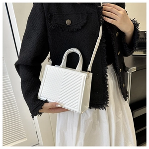 Chic white quilted mini square bag shown as crossbody style on model with black jacket