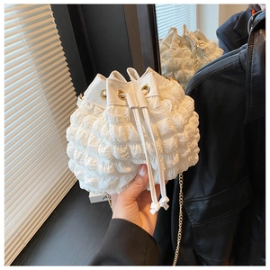 Détail du tissu à texture bulle blanche et chaîne dorée du sac seau à cordon