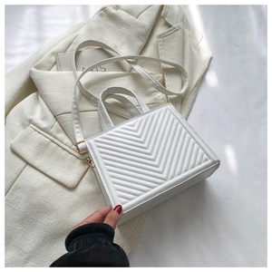 Detail of white V-quilted faux leather bag with gold hardware and top handle