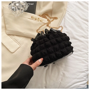 Détail du sac seau plissé noir en tissu gaufré avec une bandoulière chaîne dorée