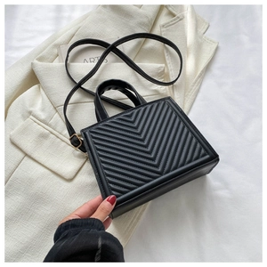 Close-up of black V-quilted faux leather bag texture with adjustable shoulder strap