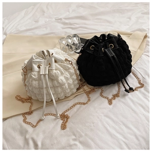 Détail de sacs seaux à texture bulles avec chaînes dorées en noir et blanc