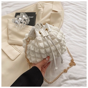 Détail de la texture gaufrée du sac seau blanc avec bandoulière chaîne dorée
