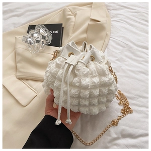 Détail du sac seau blanc à texture gaufrée avec chaîne dorée et fermeture à cordon