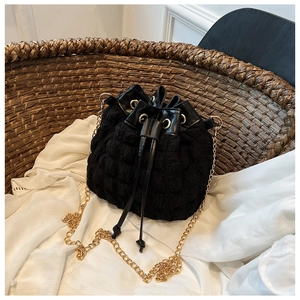Détail du sac seau noir à texture bulle avec bandoulière chaîne dorée et fermeture à cordon