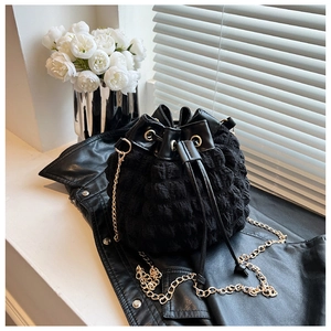 Détail macro du sac seau noir en tissu bulles avec chaîne dorée et cordon de serrage