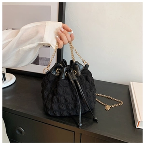 Détail du sac seau noir plissé avec bandoulière chaîne dorée et texture gaufrée