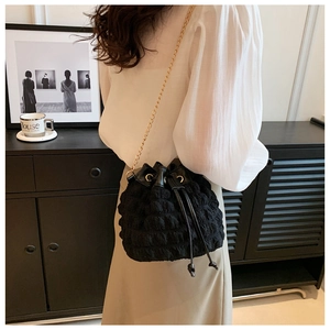 Détail du sac seau noir texturé avec chaîne dorée et fermeture à cordon coulissant