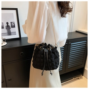 Détail du sac seau à bulles avec chaîne dorée porté à l'épaule par un mannequin