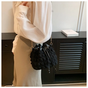 Détail du sac seau noir à texture bulles avec fermeture à cordon et bandoulière chaîne