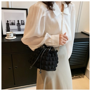 Détail du sac seau noir avec texture bulle et bandoulière en chaîne dorée chic