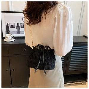 Détail du sac seau noir plissé avec chaîne dorée et finition en tissu à bulles texturé