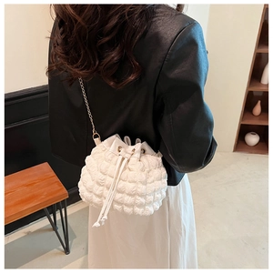 Détail d'un sac seau blanc à effet froncé avec chaîne dorée et cordon de serrage
