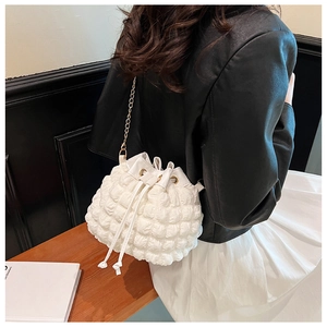 Détail du sac seau blanc à texture bulle avec bandoulière chaîne dorée sur mannequin