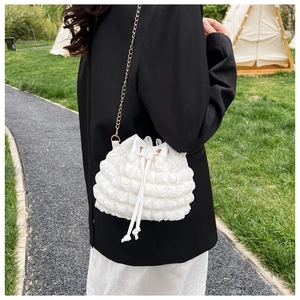 Détails de la texture bulle du sac seau blanc avec chaîne dorée et cordon de serrage