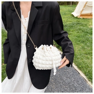 Détail du sac seau blanc à texture gaufrée avec bandoulière chaîne dorée et cordon