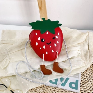 Detail of red strawberry kid bag with cartoon face, green leaves, and tiny boot charms