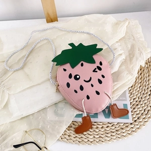 Detail of pink strawberry crossbody bag featuring cute winking face and tiny boot charms
