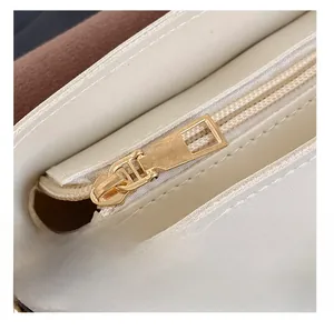 Detail showing smooth gold metal zipper and creamy white faux leather texture