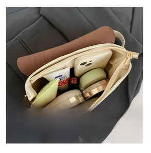 Top view of cream shoulder bag interior showing spacious storage for makeup and phone