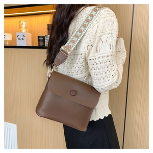 Brown leather crossbody bag with colorful ethnic jacquard strap on a model shoulder